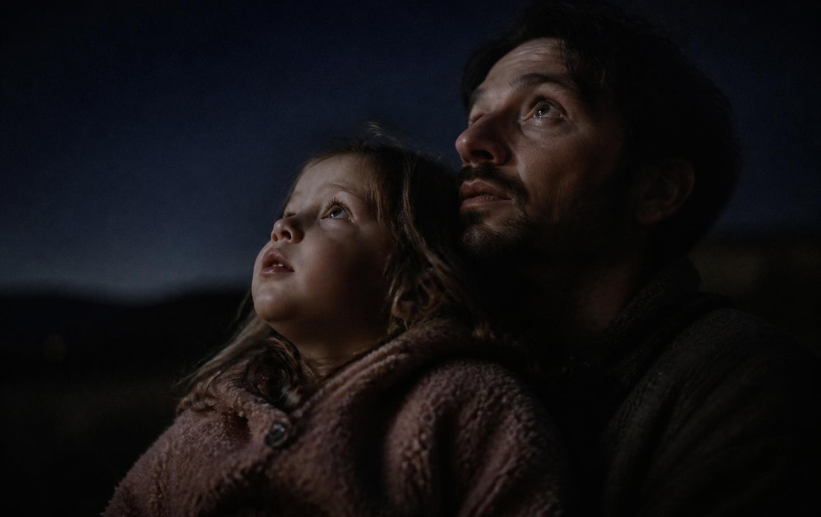 A parent and a young child looking up at the night sky together